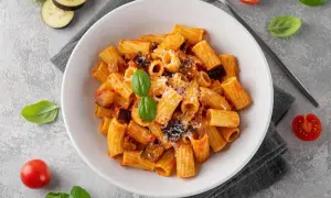 En skål med pasta norma, en klassisk siciliansk rätt med aubergine och tomatsås, toppad med basilika och parmesan.