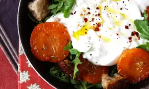 En krämig italiensk ost burrata serveras med ugnsrostade tomater, ruccola och krutonger.