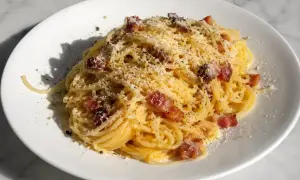 En portion krämig pasta carbonara med knapriga bitar av pancetta och rikligt med riven parmesanost.