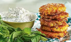 En stapel gyllene halloumi och morotsbiffar serveras med en krämig yoghurtsås och färsk mynta.
