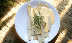 Vit sparris serverad med en krämig sås och toppad med färska groddar. En klassisk vårrätt som smakar ljuvligt.