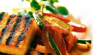 Grillad polenta med saftiga grönsaker som zucchini och paprika, toppad med färska örter. En härlig sommarrätt.