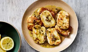 Stekt, marinerad halloumi med en kryddig dressing och chiliflakes. Serveras på en tallrik med citronklyftor vid sidan.