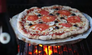 En grillad pizza med tomater, champinjoner och oliver. Perfekt för ett enkelt pizzadeg recept.