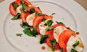 Caprese-sallad med skivade tomater, färsk mozzarella och basilika. Ett enkelt och gott mozzarella recept.