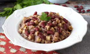 En skål med krämig pasta fagioli, toppad med färska bönor och persilja. Ett härligt recept för en mysig middag.