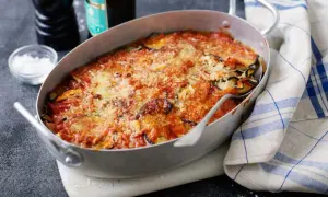 En ugnsform med en gyllene, bubblande melanzane alla parmigiana, toppad med smält ost och tomatsås.