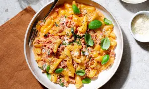 En skål med pasta alla norcina, krämig och toppad med färsk basilika och riven parmesan.