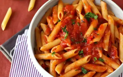 En skål med penne pasta arrabiata, toppad med färsk persilja. Enkel och smakrik italiensk klassiker.