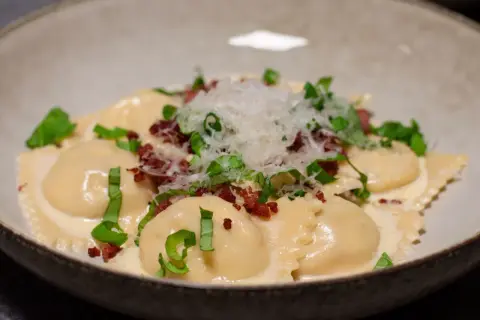 Ravioli salsiccia i krämig sås, toppad med riven parmesan och färska örter. En läcker italiensk rätt.