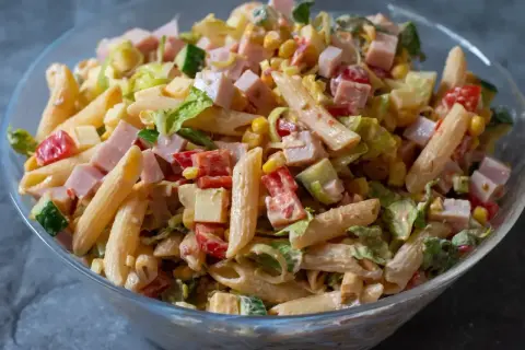 En stor skål med pastasallad med kassler, penne, majs, gurka, tomat och ost. En perfekt sommarmåltid!