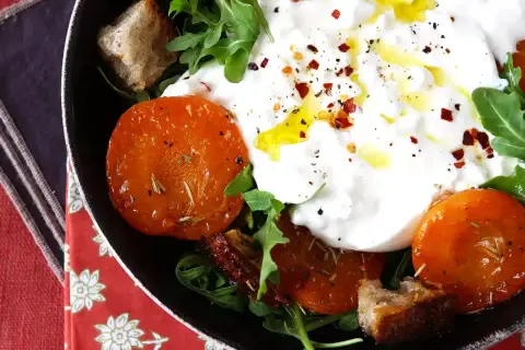 En krämig italiensk ost burrata serveras med ugnsrostade tomater, ruccola och krutonger.