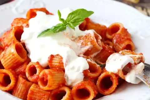 En krämig portion rigatoni med tomatsås och en generös klick stracciatella pasta, toppad med färsk basilika.