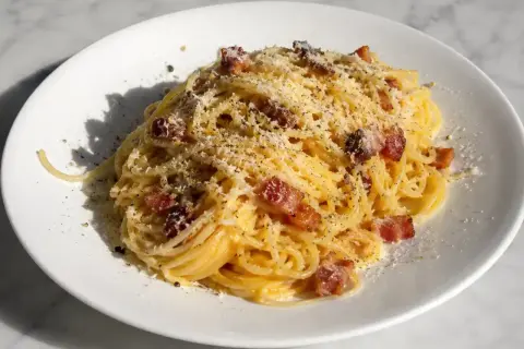 En portion krämig pasta carbonara med knapriga bitar av pancetta och rikligt med riven parmesanost.