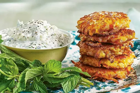 En stapel gyllene halloumi och morotsbiffar serveras med en krämig yoghurtsås och färsk mynta.