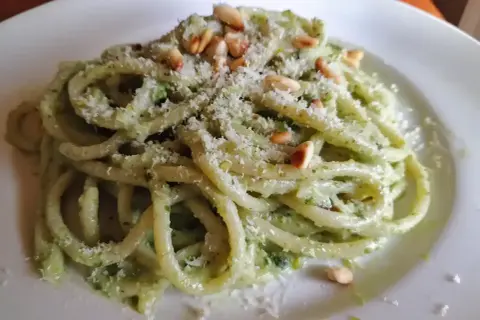 En tallrik med krämig pasta pesto, toppad med pinjenötter och riven parmesan. En härlig italiensk klassiker.