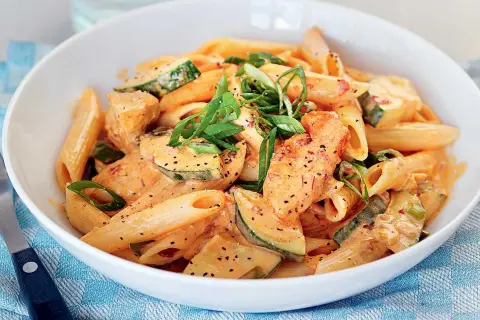 Enkel pasta med kyckling och zucchini i krämig tomatsås, toppad med salladslök.