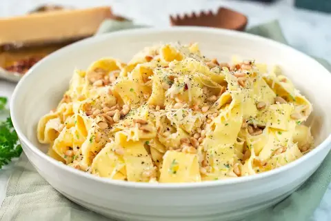 En skål med krämig citronpasta, toppad med pinjenötter och riven parmesan. En härlig rätt som passar perfekt för en snabb och smakrik middag.