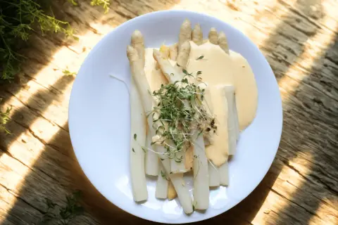 Vit sparris serverad med en krämig sås och toppad med färska groddar. En klassisk vårrätt som smakar ljuvligt.