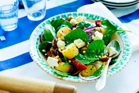 En härlig potatissallad med fetaost, spenat, oliver och soltorkade tomater. Perfekt till sommarlunchen!