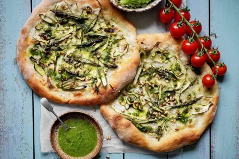 Två läckra, gröna pizzor med sparris och pinjenötter, som en sommar i Rom. Serveras med en skål pesto.