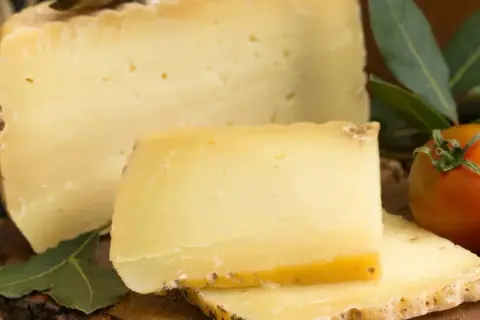 En bit pecorino ost med tomater och gröna blad.