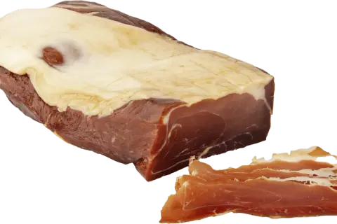 En bit prosciutto crudo med tunt skivad skinka bredvid.