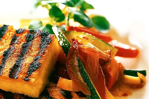 Grillad polenta med saftiga grönsaker som zucchini och paprika, toppad med färska örter. En härlig sommarrätt.