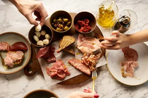 En härlig italiensk charkbricka med oliver, soltorkade tomater, mozzarella, bröd och olika sorters charkuterier.
