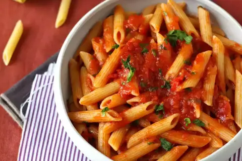 En skål med penne pasta arrabiata, toppad med färsk persilja. Enkel och smakrik italiensk klassiker.