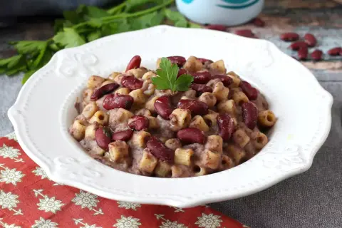 En skål med krämig pasta fagioli, toppad med färska bönor och persilja. Ett härligt recept för en mysig middag.