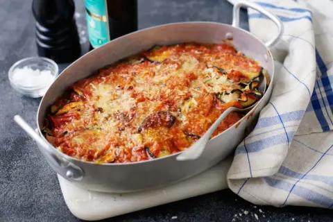 En ugnsform med en gyllene, bubblande melanzane alla parmigiana, toppad med smält ost och tomatsås.