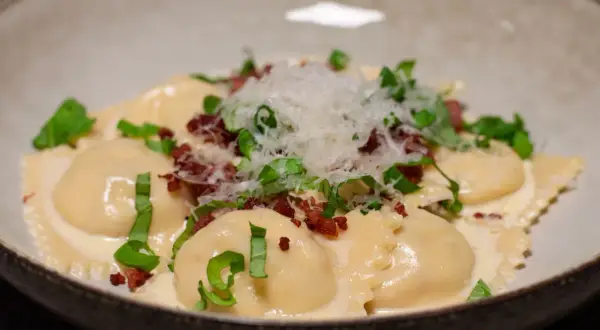 Ravioli salsiccia i krämig sås, toppad med riven parmesan och färska örter. En läcker italiensk rätt.
