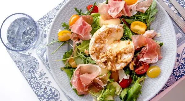 En härlig sallad med prosciutto, krämig ost med nötter, körsbärstomater och gröna blad. En perfekt sommarrätt.