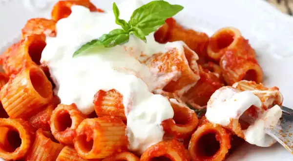 En krämig portion rigatoni med tomatsås och en generös klick stracciatella pasta, toppad med färsk basilika.