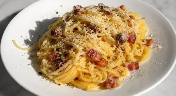 En portion krämig pasta carbonara med knapriga bitar av pancetta och rikligt med riven parmesanost.