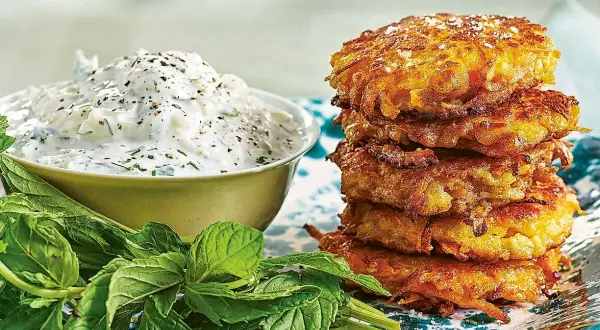 En stapel gyllene halloumi och morotsbiffar serveras med en krämig yoghurtsås och färsk mynta.