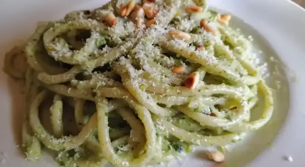 En tallrik med krämig pasta pesto, toppad med pinjenötter och riven parmesan. En härlig italiensk klassiker.
