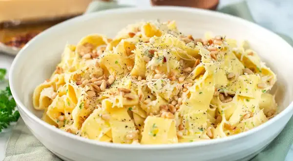 En skål med krämig citronpasta, toppad med pinjenötter och riven parmesan. En härlig rätt som passar perfekt för en snabb och smakrik middag.