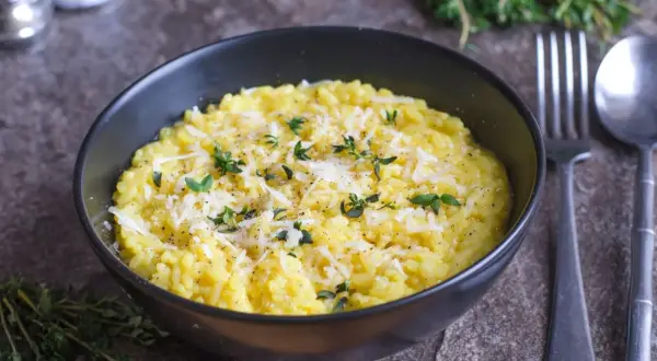 En krämig risotto alla milanese, toppad med riven parmesan och färska örter.