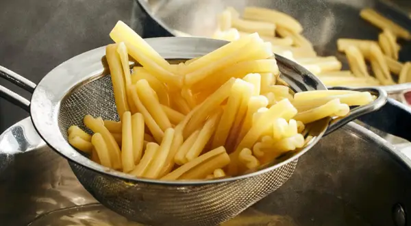 Nyskördade durumvete pasta i ett durkslag, redo att serveras.
