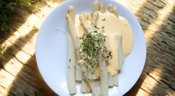 Vit sparris serverad med en krämig sås och toppad med färska groddar. En klassisk vårrätt som smakar ljuvligt.