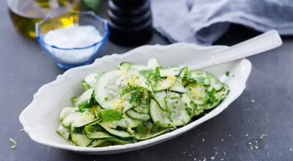 En fräsch zucchini sallad med citronzest och örter, serverad i en vit skål.