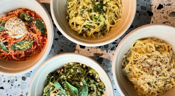 Fyra skålar med pasta, en med röd sås och burrata, en med pesto och pinjenötter, och två med ost och peppar. En hyllning till cucina povera.