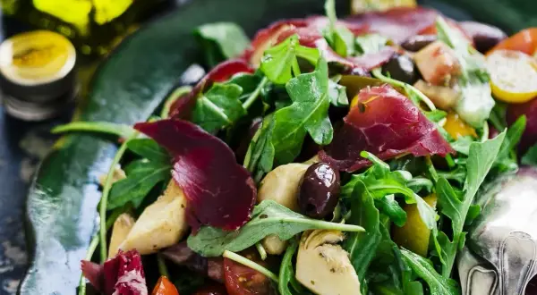 En härlig typisk italiensk sallad med ruccola, lufttorkat kött, oliver, kronärtskocka och tomater.
