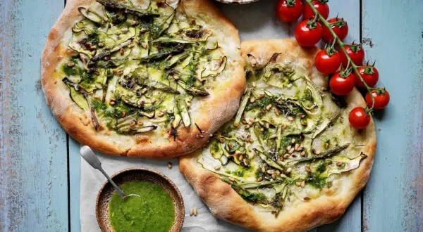 Två läckra, gröna pizzor med sparris och pinjenötter, som en sommar i Rom. Serveras med en skål pesto.