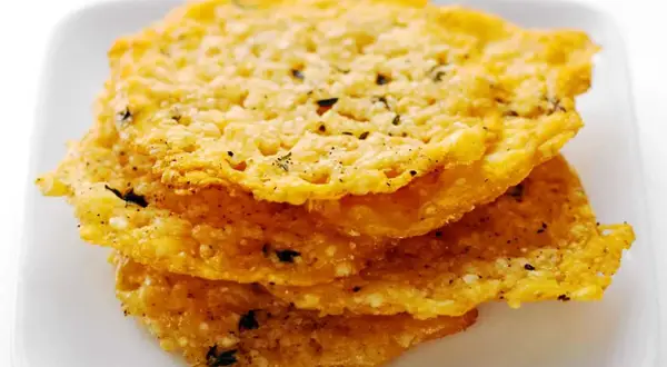 Krispiga, gyllene pasta chips med örter och peppar staplade på en vit tallrik. Perfekt som tilltugg!