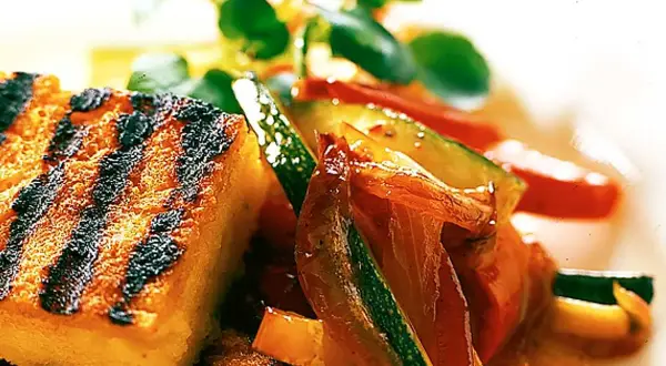 Grillad polenta med saftiga grönsaker som zucchini och paprika, toppad med färska örter. En härlig sommarrätt.