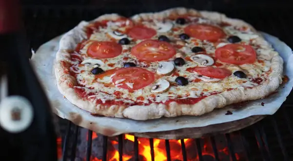 En grillad pizza med tomater, champinjoner och oliver. Perfekt för ett enkelt pizzadeg recept.