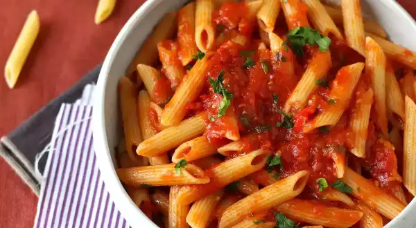 En skål med penne pasta arrabiata, toppad med färsk persilja. Enkel och smakrik italiensk klassiker.